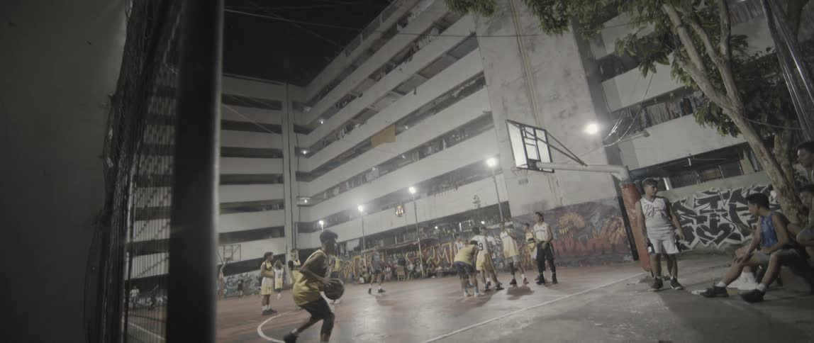 Teenagers play on an outdoor basketball court