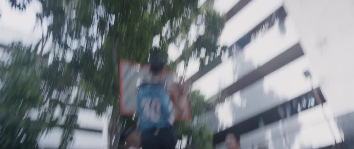 Boys are playing basketball on a community court in daylight