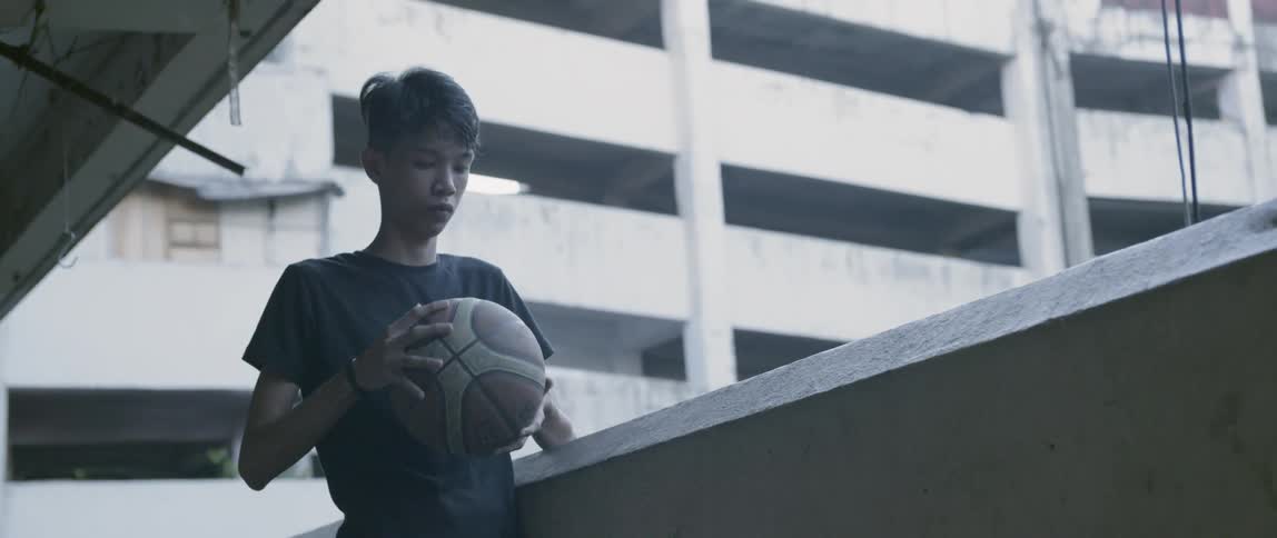 Teenager holds a basketball on a balcony