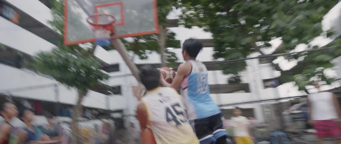 Boys play basketball on an outdoor urban court