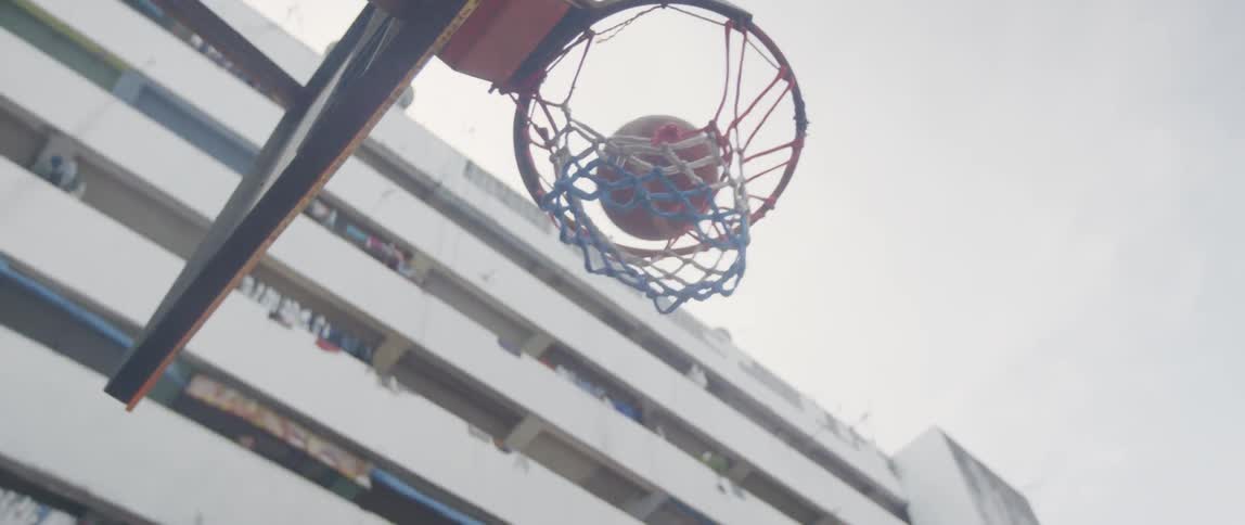 A player shoots and scores on an outdoor basketball court