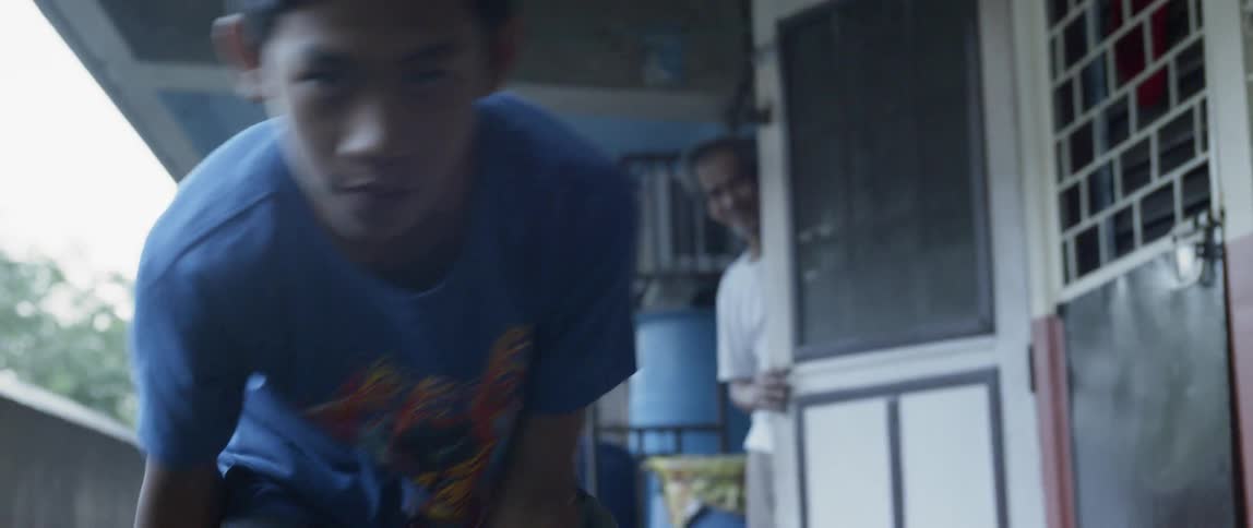 A boy is dribbling a basketball as he stands outside an apartment during the day