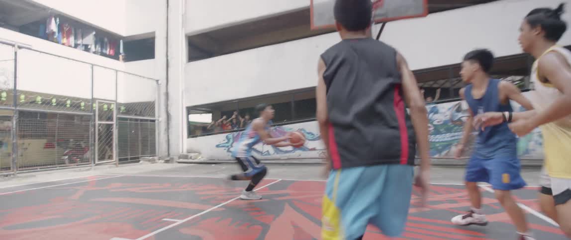 Teenagers play basketball on an outdoor court