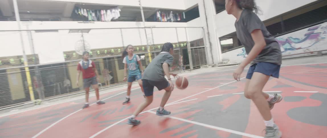 Young women play basketball together