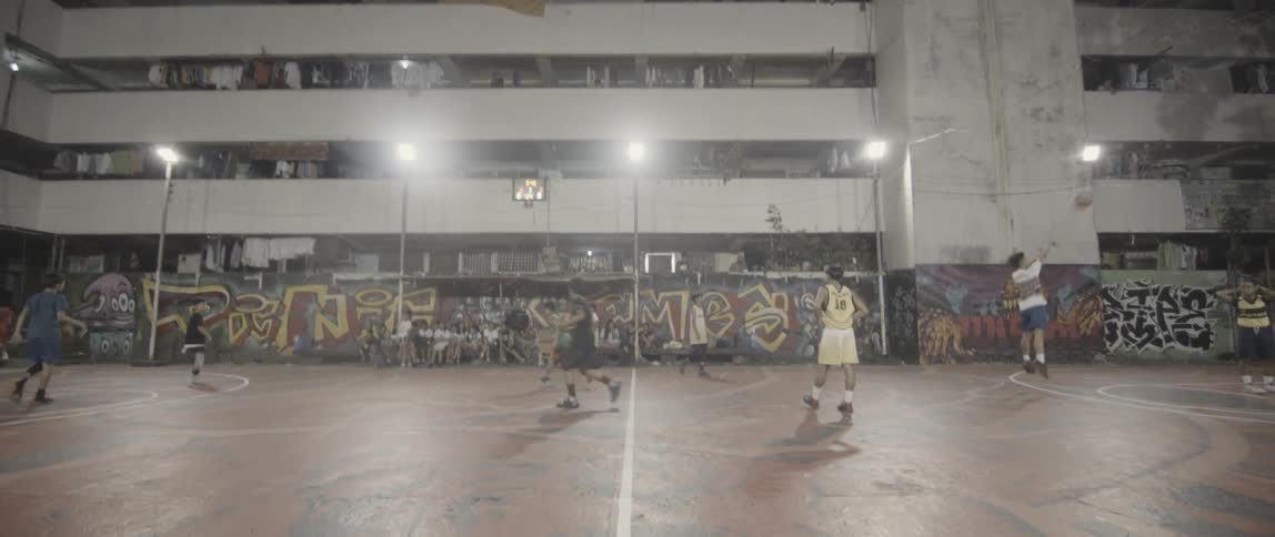 Boys play on an outdoor basketball court