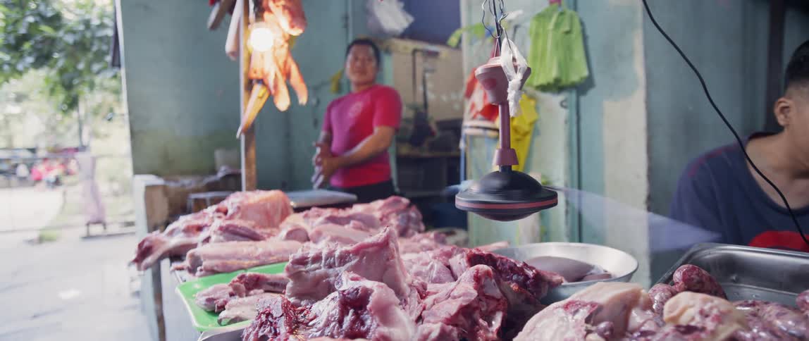 A man stands near a table full of meat