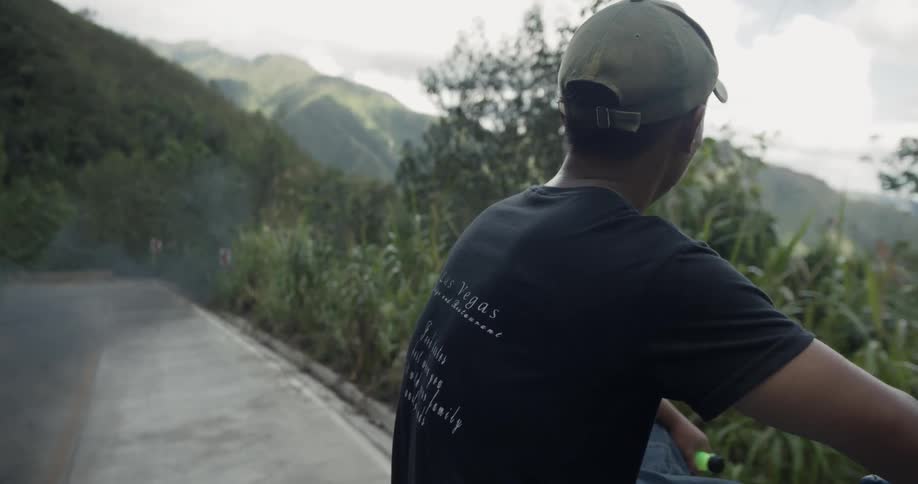 Man rides on top of a vehicle on a mountain road