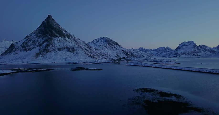 Snowy mountains surround a lake at dusk