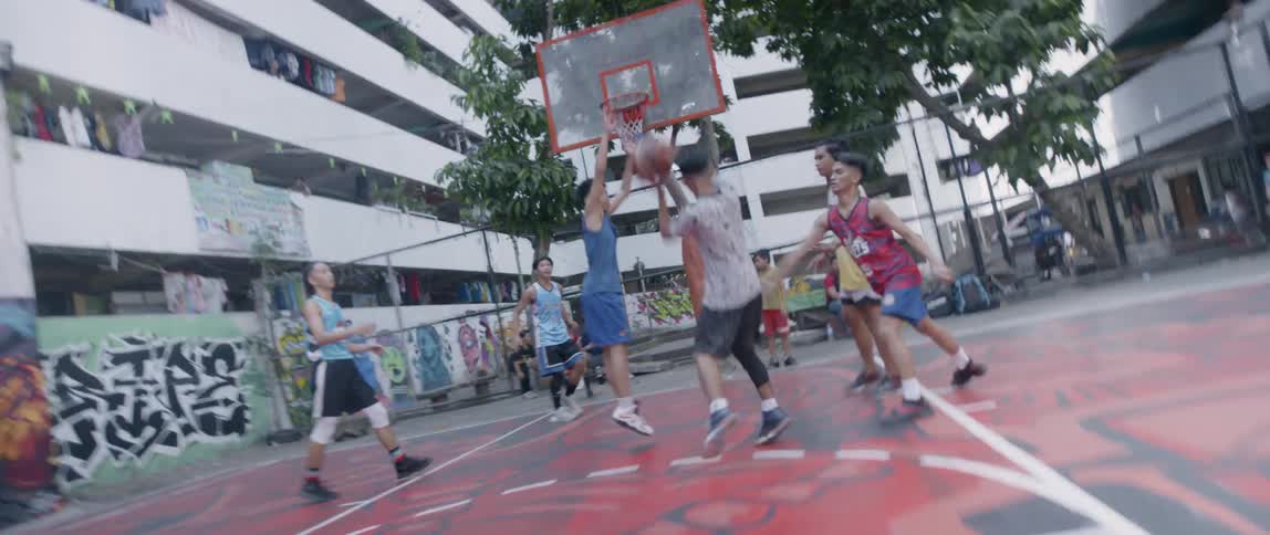 Teenagers play basketball in a courtyard