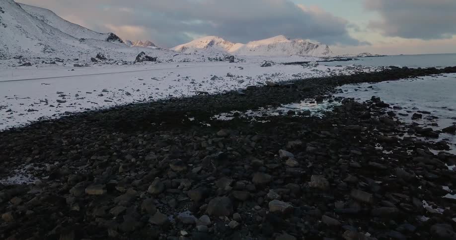 Snow covered rocks lay next to the lake