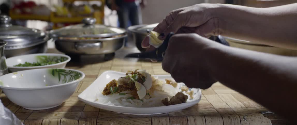 Person slices egg onto a plate of food