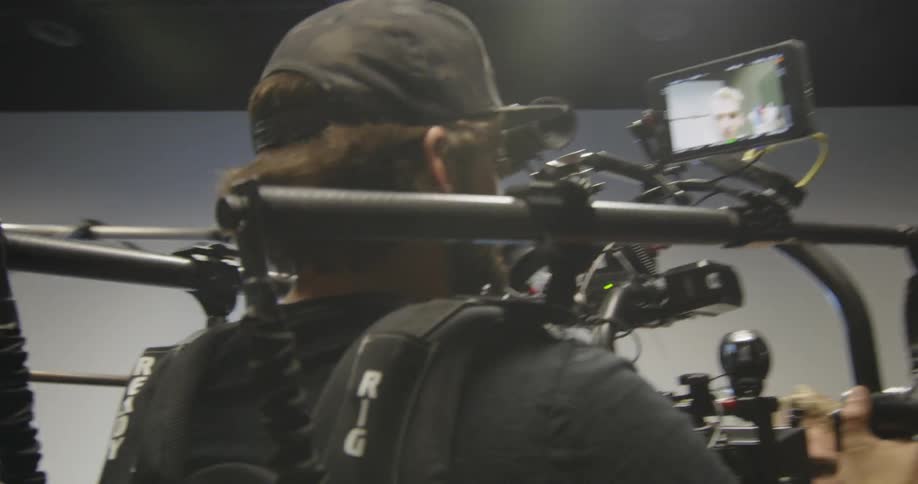 Man holds a video camera apparatus as he moves around the room