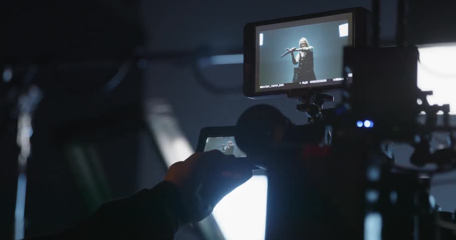 A cameraman adjusts a monitor as video plays back