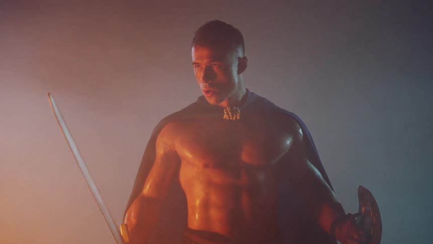 A gladiator stands near a smoky fire