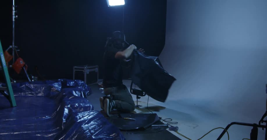 Man places plastic around a studio light fixture