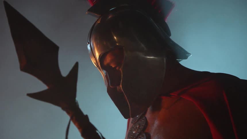 A roman warrior holds a spear and looks down
