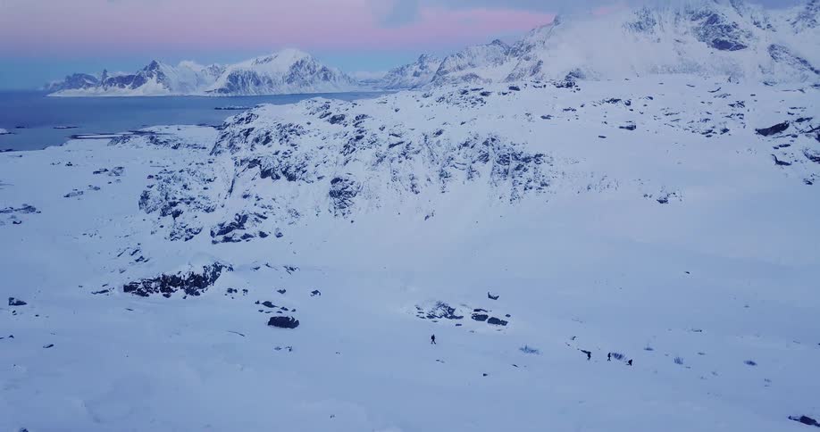 A group of people are trekking in a rugged landscape in winter