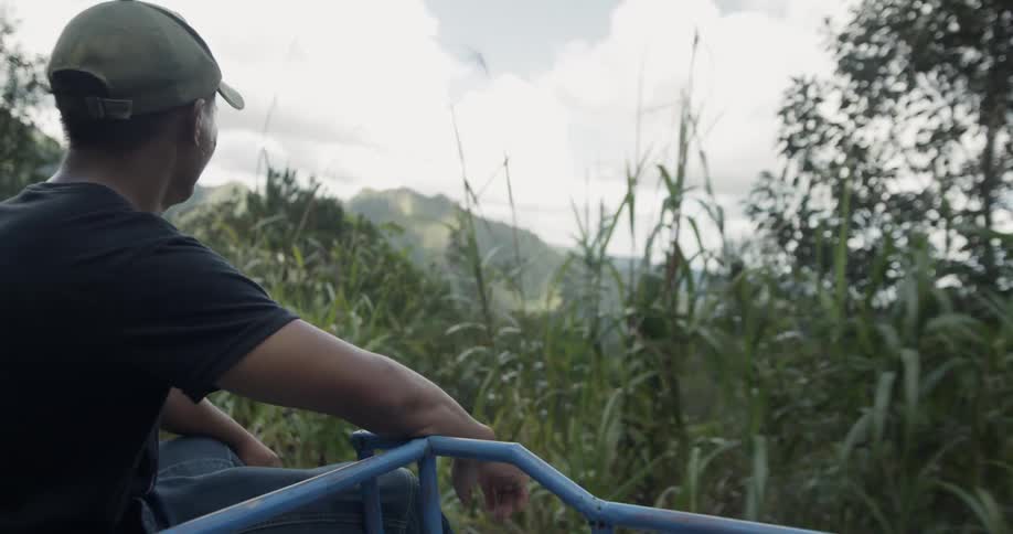 A man looks down at the trees as he rides up a hill
