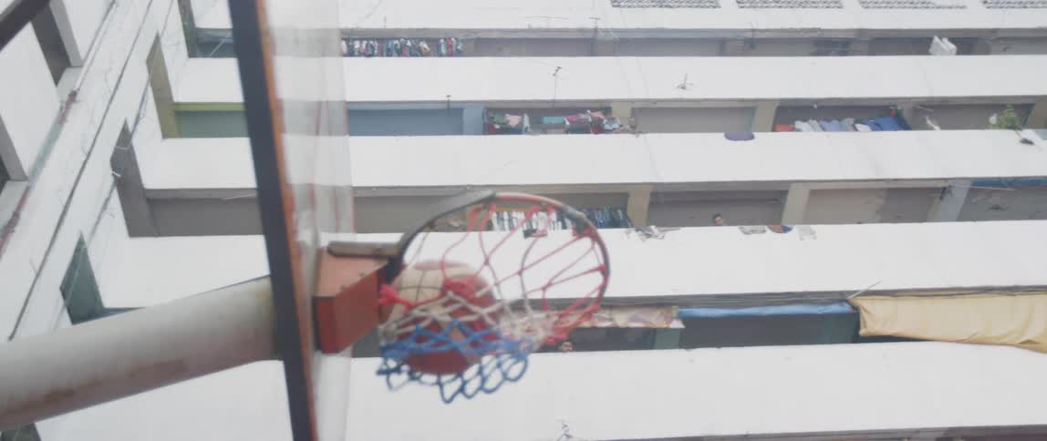 Girl ducks around other people and shoots a basketball into a hoop