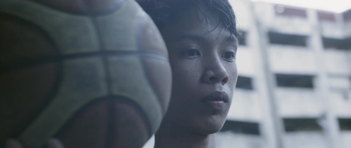 Man holds a basketball as he stares ahead
