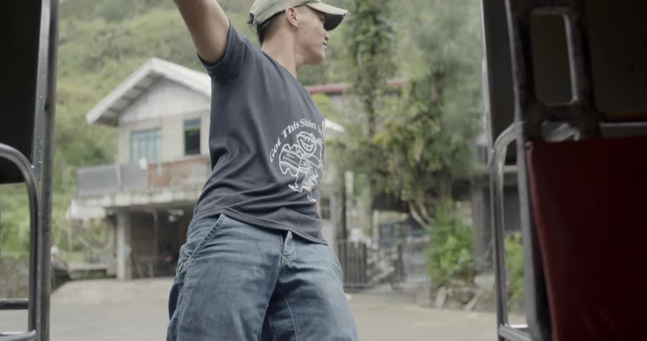 A man hangs outside of a moving vehicle