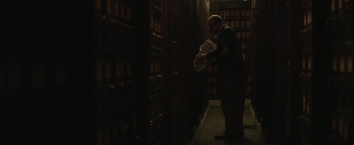 A man removing files and periodicals from storage shelves