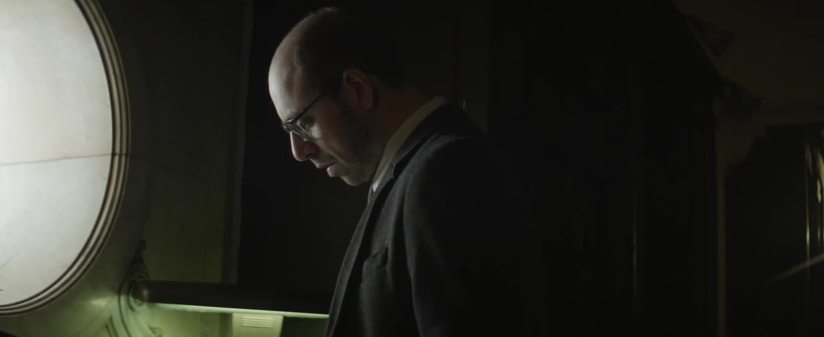 Man wearing glasses looking down in a dark room