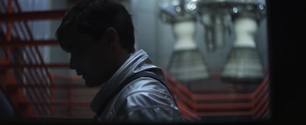 A man in a silver suit stands lost in thought