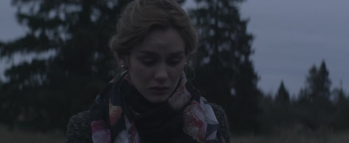 Woman looks around sadly outdoors at twilight