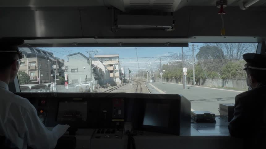 Conductor drives a train down the tracks under a blue sky