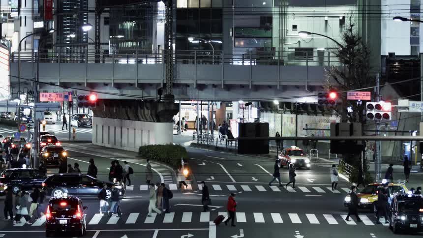 Pedestrians cross a city street at night