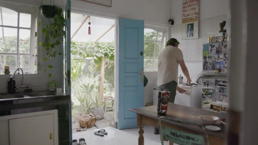 A man is lighting the burner on a stove inside in daylight