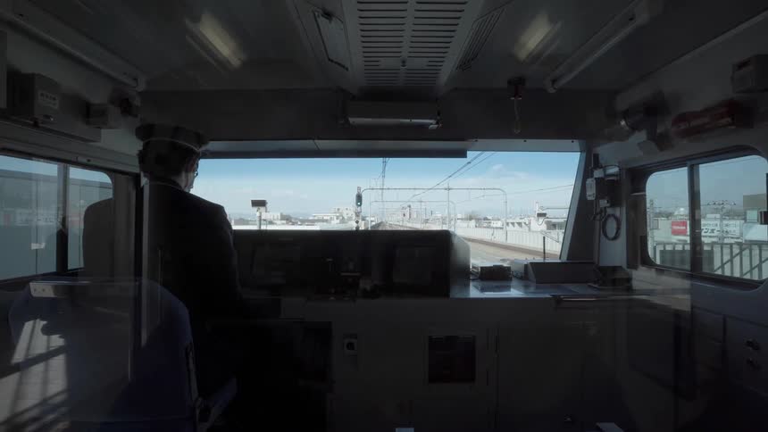 A train conductor is taking his seat inside the train during the day