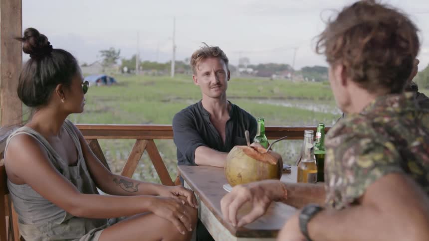 Group of friends sit on a deck with drinks and talk