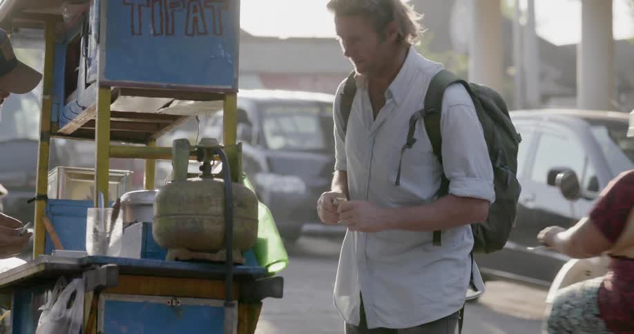 A man walks over to a stand to make a purchase