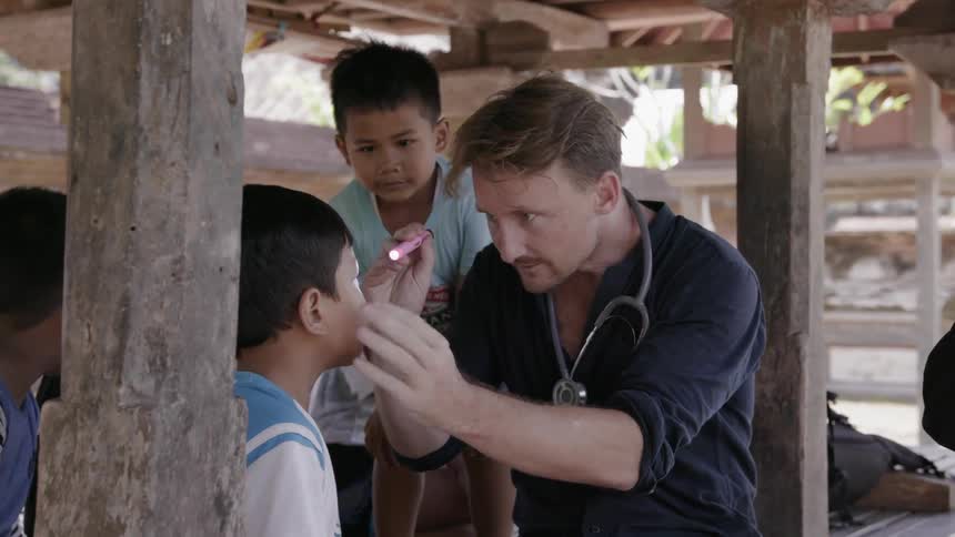 A physician examines young boys in a village