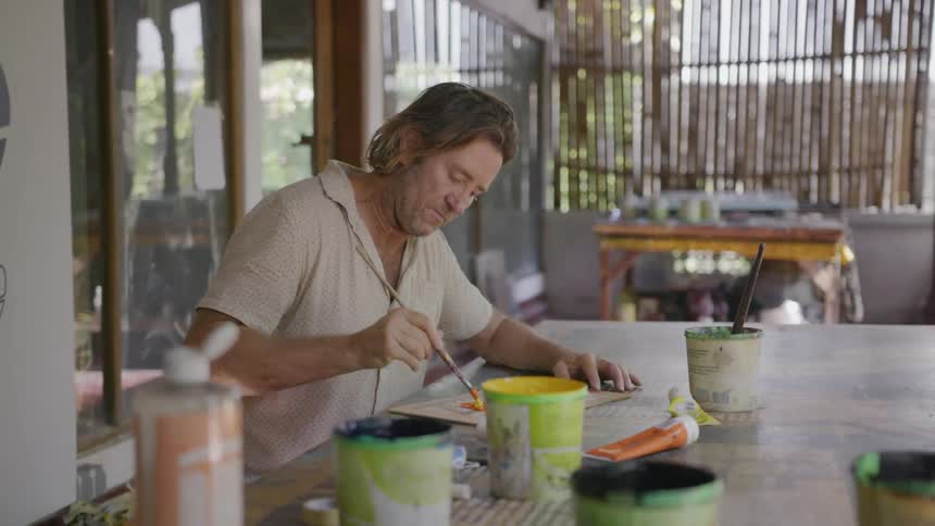 Man paints at a patio table