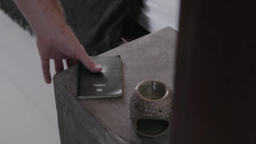 Man picks up a passport from a nightstand