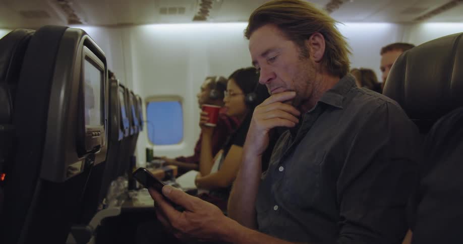 Man uses his phone on an airplane