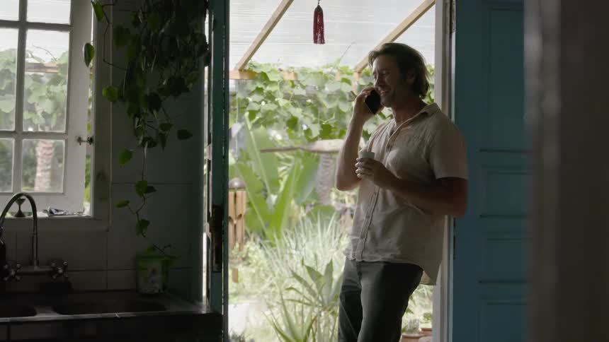 A man leans against a doorway and talks on the phone