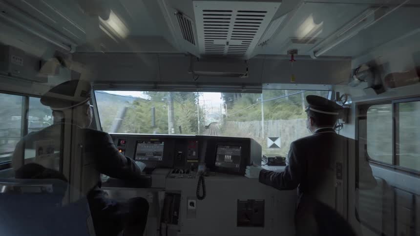 Two men driving a train through a city