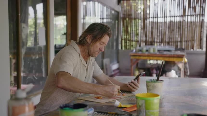 A man is sitting at the table painting