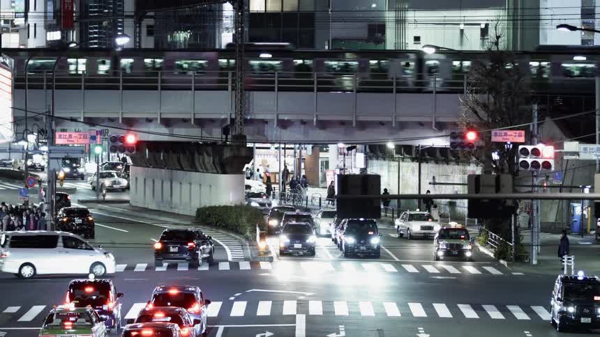 Traffic travels on the streets under a bridge as a train moves overhead