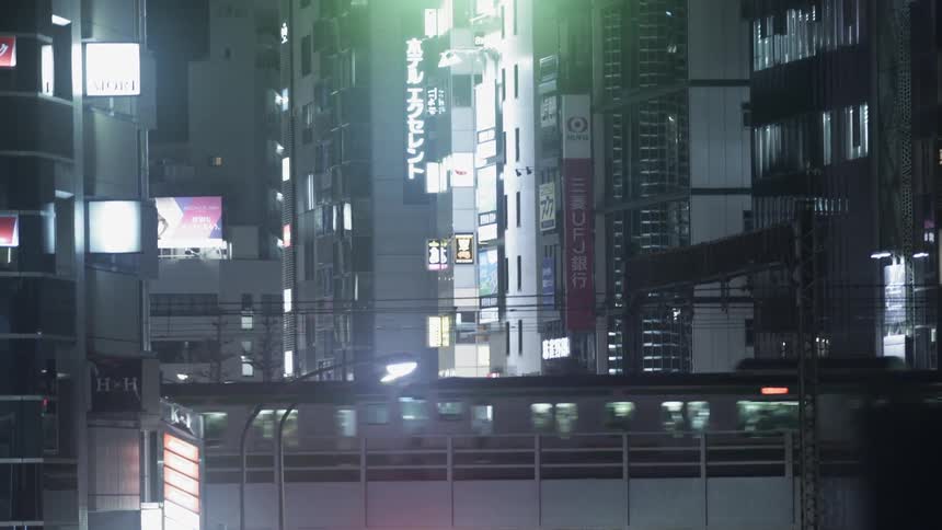 A commuter train is passing over a bridge in an asian city at night