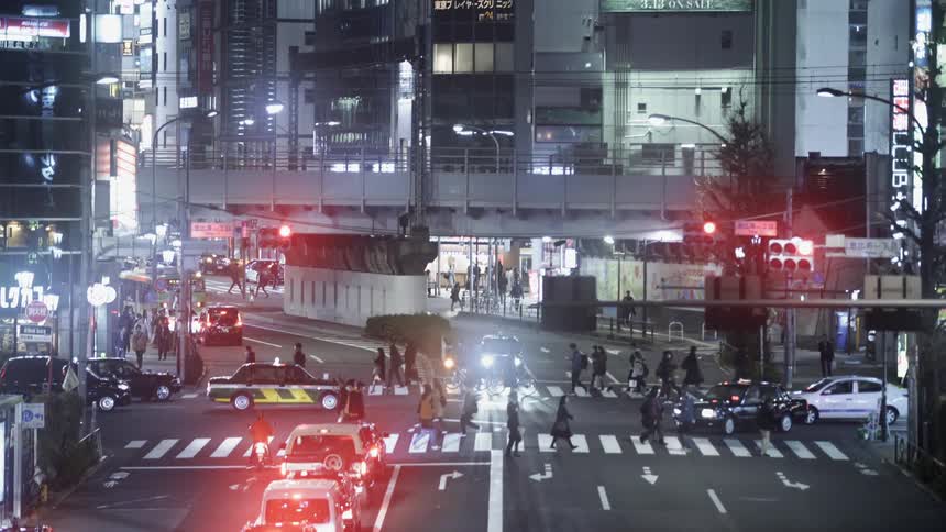 Pedestrians cross a city street at night