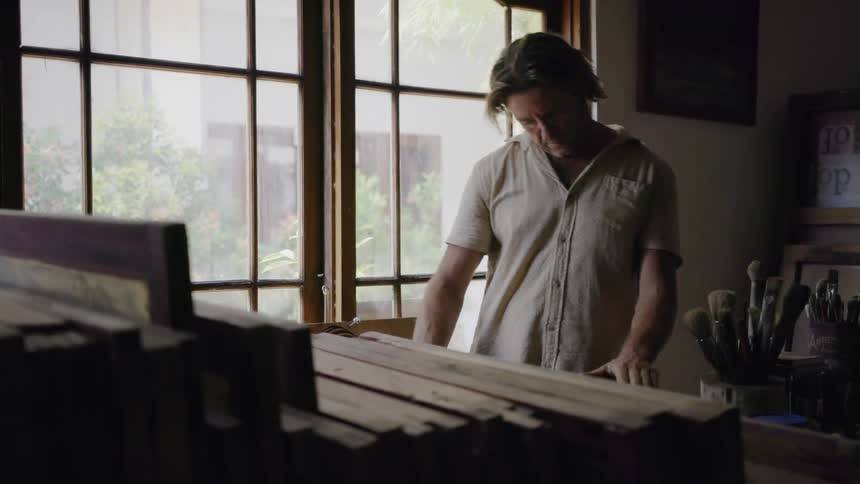 A man browses through stacked canvas paintings