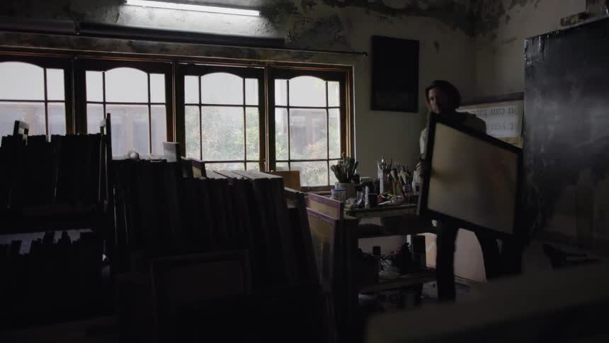 Man carries paned glass in an art studio