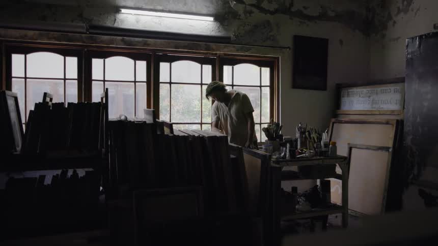 Man looks through stacks of canvases in an art studio