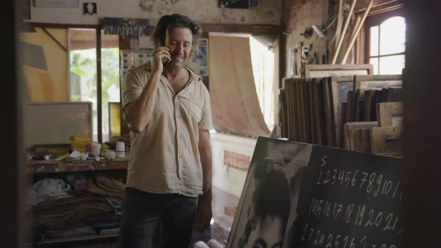 A man gestures toward artwork as he talks on the phone