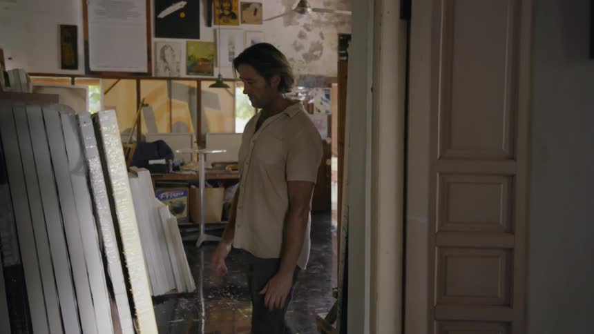 An artist looks at stacked canvas paintings